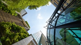 Low angle shot of modern glass buildings and green with clear sky background